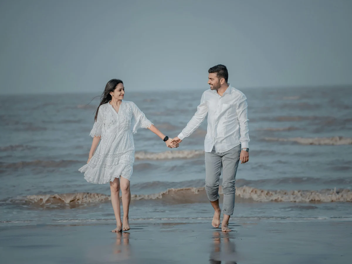 Smiling Couple Holding Hands and Walking on Sea Shore