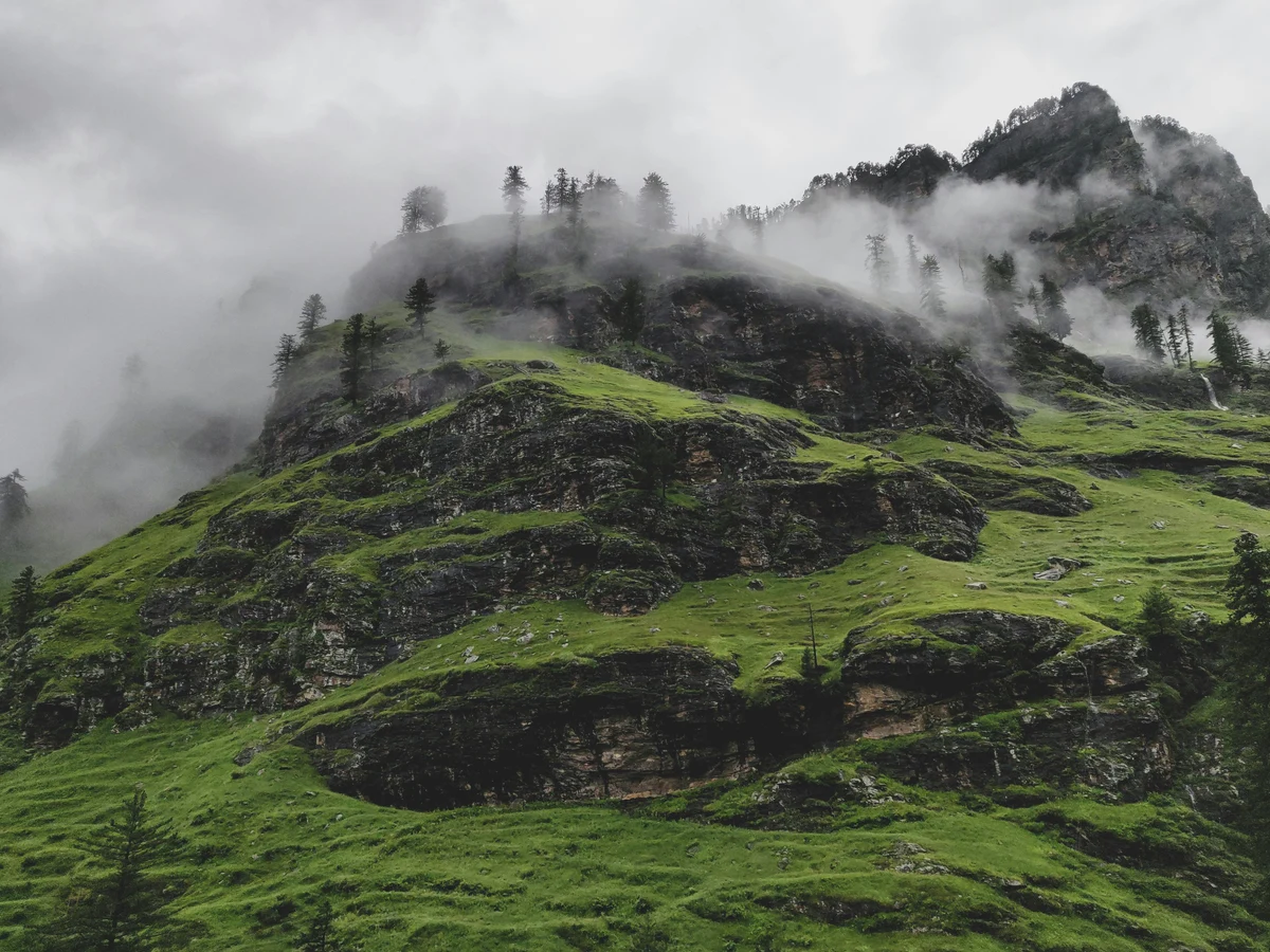 Green Grass Covered Mountain Under Cloudy Sky