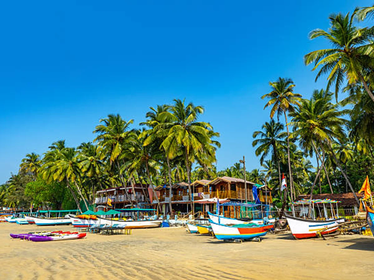 Sunny Beach Scene in Goa with Colorful Boats and Palm Trees