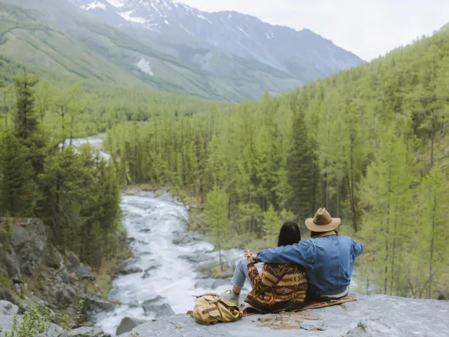 A Couple Sitting on the Rock Looking the Mountain View