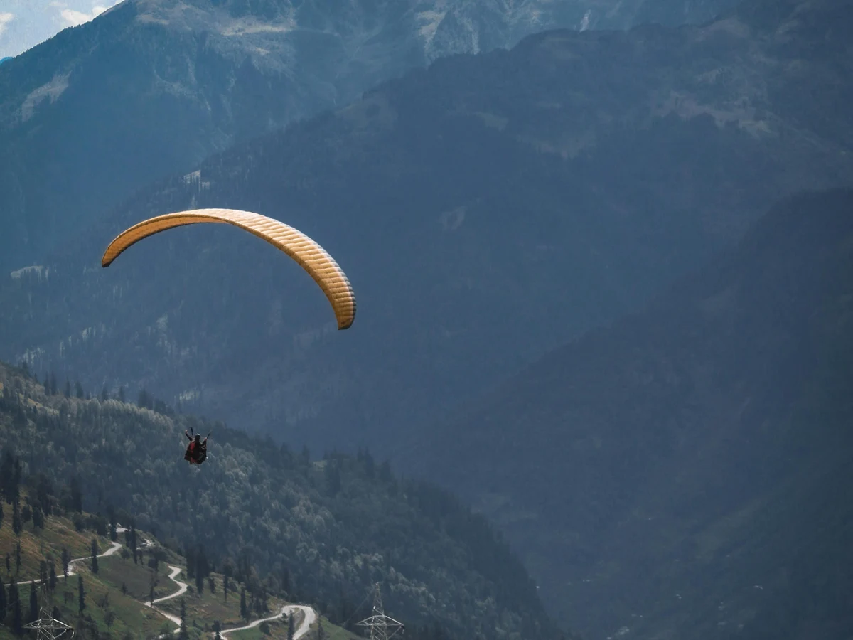 Person Riding Yellow Parachute over Mountain Range