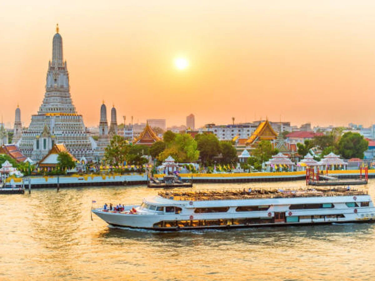 Chao Phraya River Cruise Boat with Temple Wat Arun, at Sunset in Background,