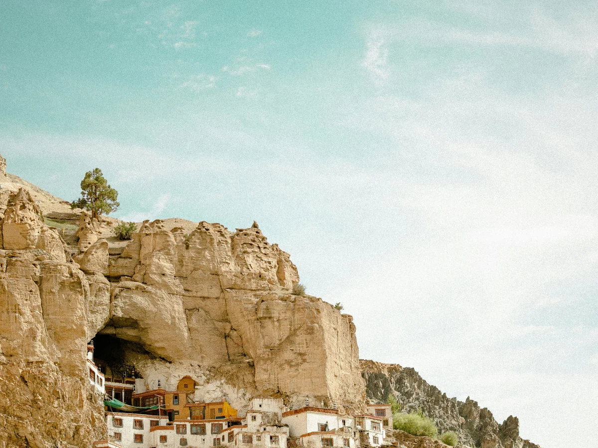 Monastery built into a steep mountain cliff under blue sky