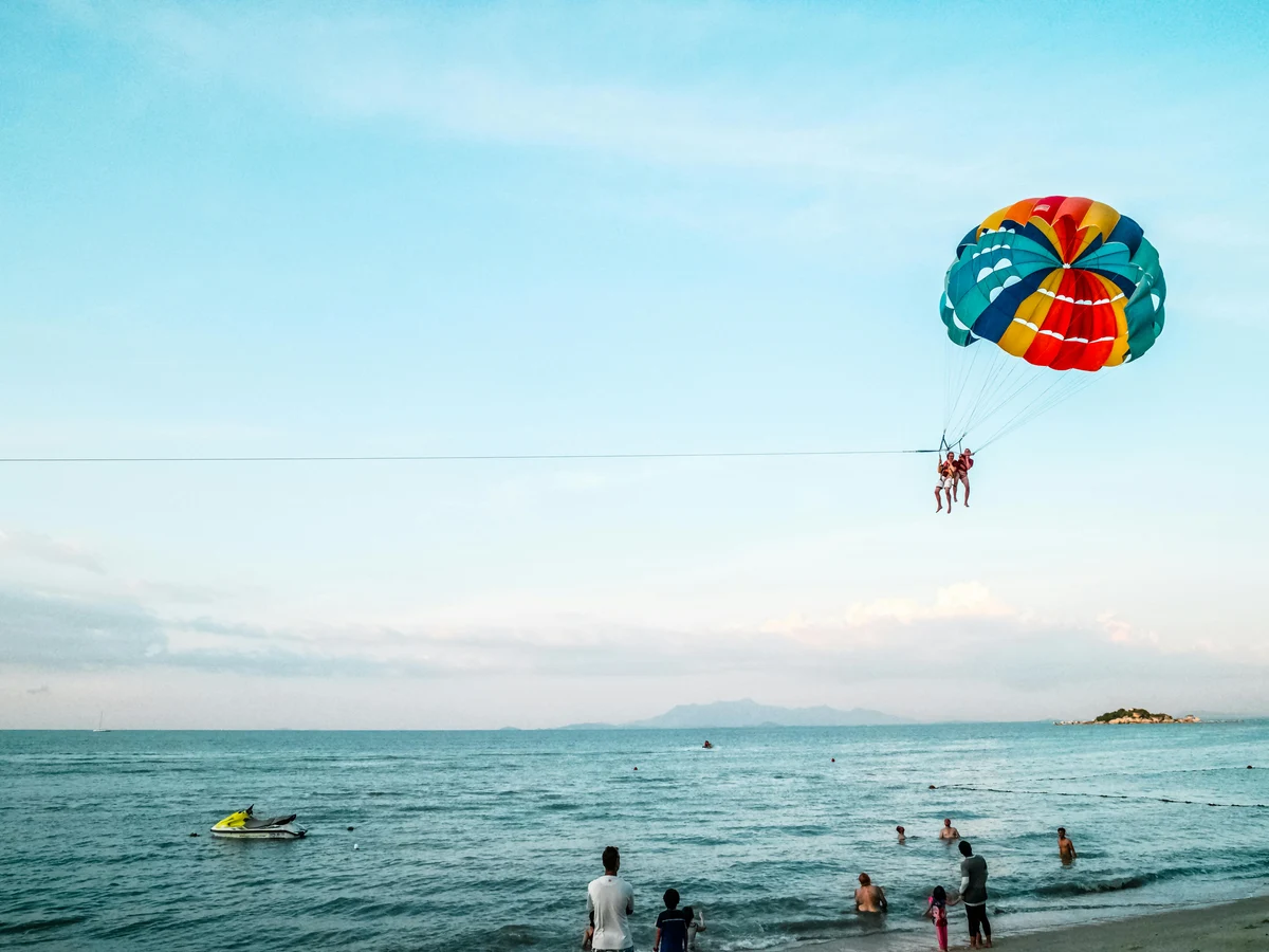 Person Riding Parachute Above Ocean